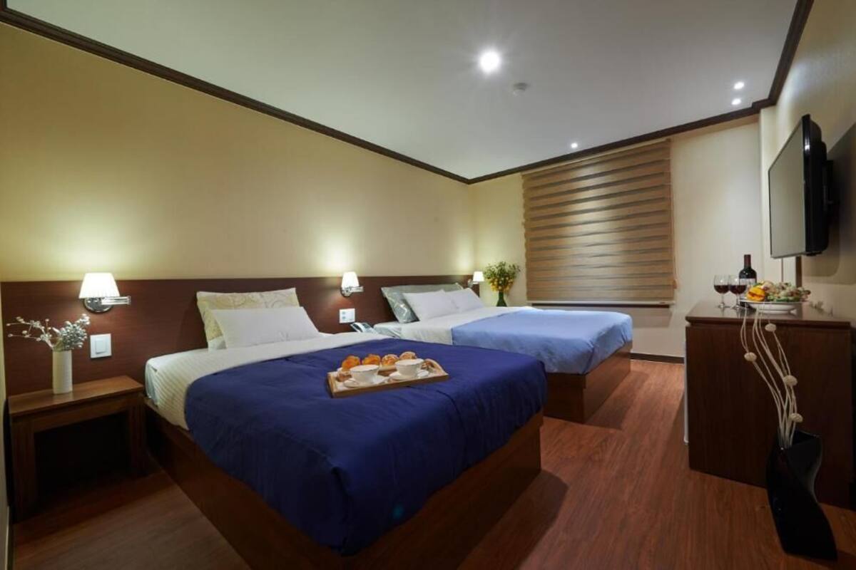 A hotel room with two beds, a TV, and a small table with a tray of food.