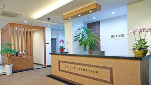 A reception desk with a wooden finish and a sign that reads "INFORMATION". There are potted plants on the desk and a wall-mounted sign with Japanese characters. - Fourseasons Hotel (Jeju City)