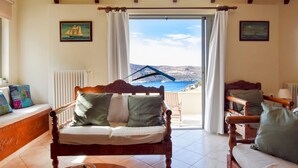 Una habitación acogedora con una cama y una silla de madera, y vistas al mar a través de un ventanal grande.