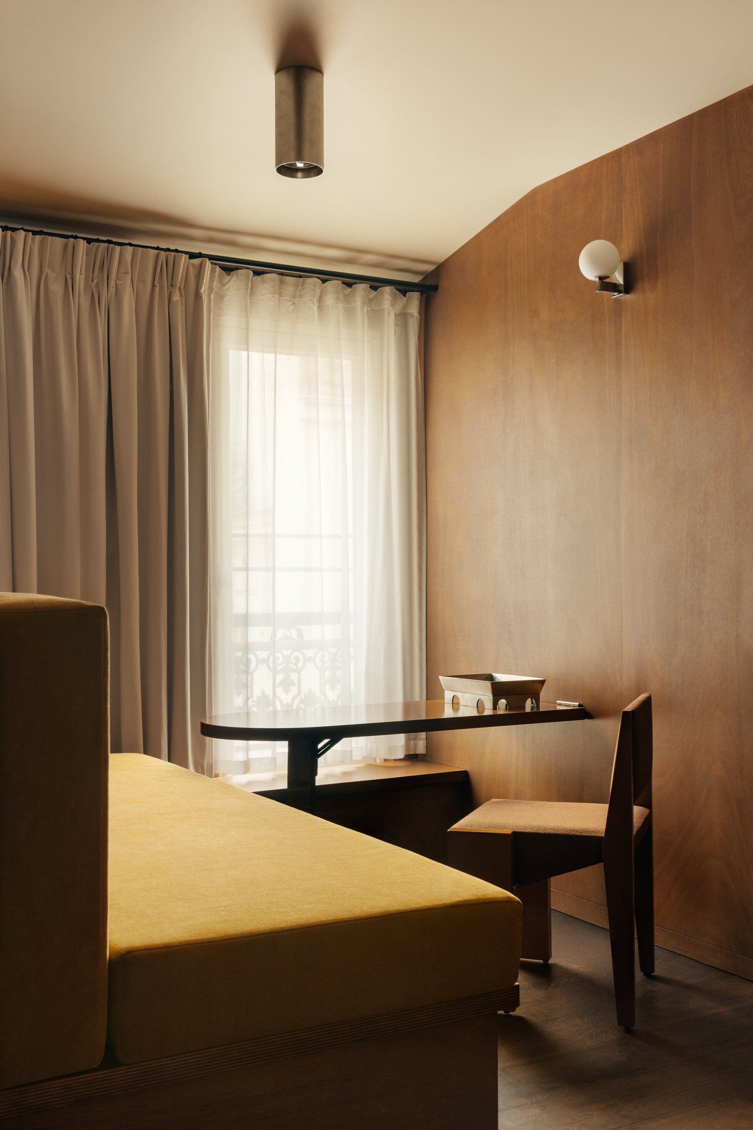 Une chambre d’hôtel moderne avec un mur d’accent en bois, une table à manger avec une chaise et un canapé.