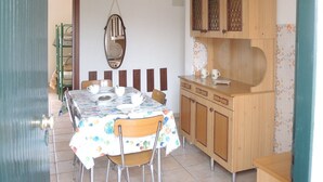 A dining area with a table set for four, wooden cabinets, a hanging light fixture, and a mirror on the wall. - Adorable Flat 250 m From the Beach - Beahost (San Michele al Tagliamento)