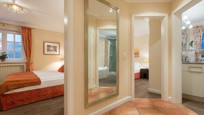 Ein Hotelzimmer mit einem Bett, einem großen Spiegel, einem Badezimmer mit Dusche und einer kleinen Küchenzeile.