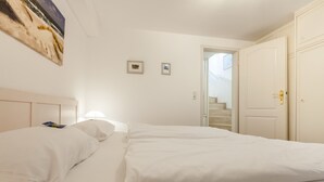 A hotel room with a large bed, a door, and a staircase leading to another room. - Abschalten, Erholen, Seelebaumeln - Das Rosenkamp Bietet Entspannung & Erholung (Sylt / OT Westerland)