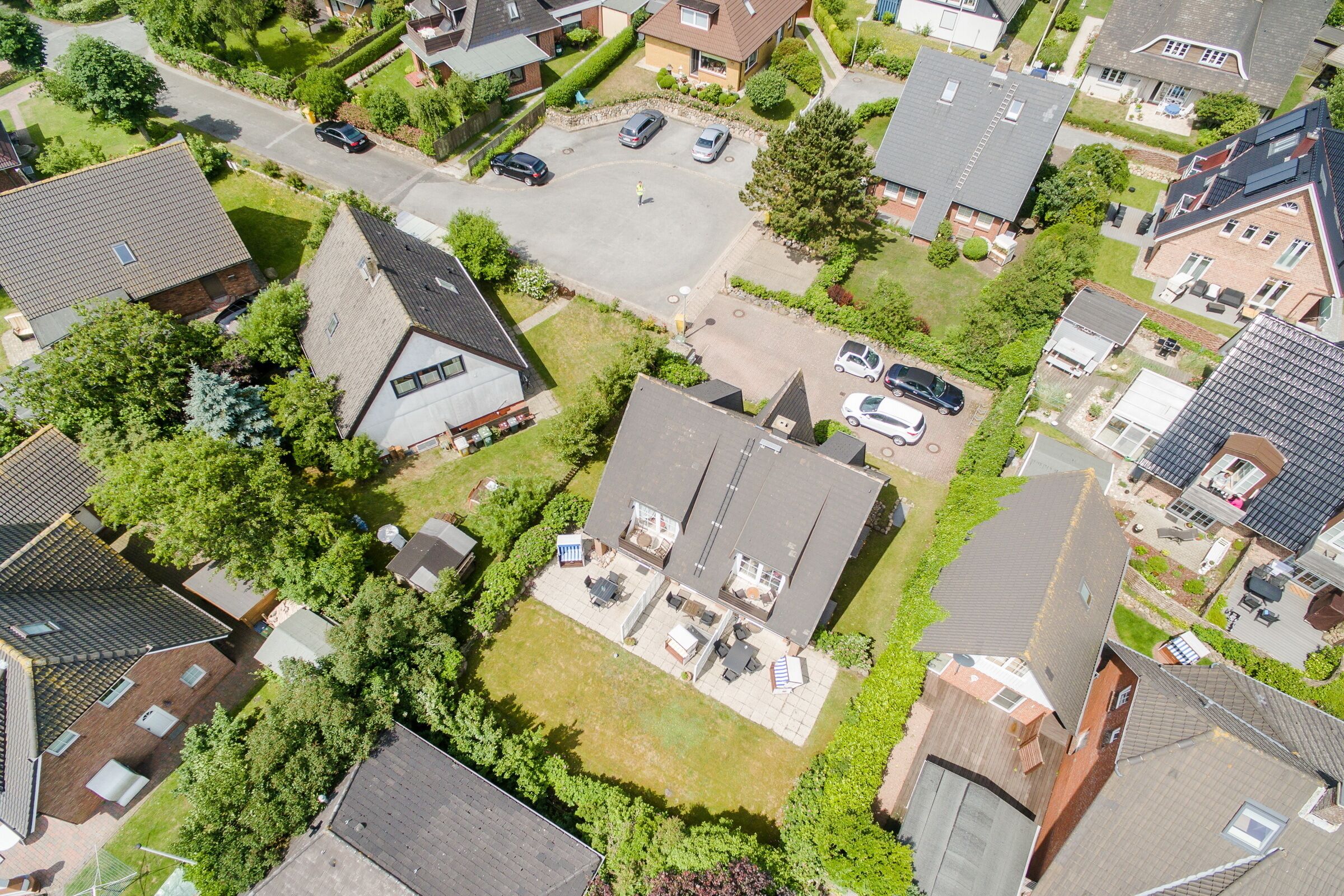 Vista aérea de una zona residencial con casas, un estacionamiento y un patio con césped.