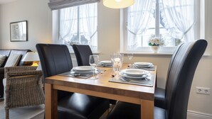 En matplats med ett träbord för fyra personer, svarta stolar och en hängande lampa.