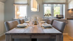 A dining area with a wooden table set for six, surrounded by leather chairs, with a hanging light fixture above. - Ein Wohntraum & Viel Mehr, Nahe dem Meer (Sylt / OT Westerland)