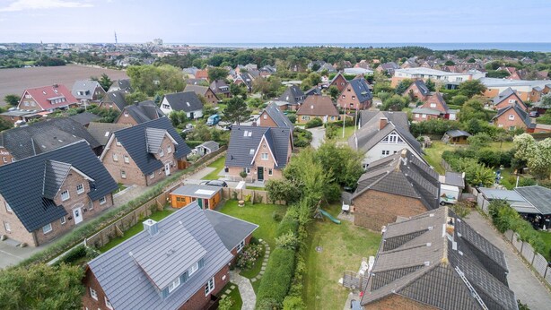 Un quartier résidentiel avec des maisons, une aire de jeux et une vue sur la mer.