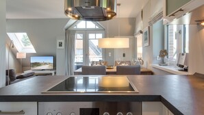 Une cuisine moderne dotée d’une plaque de cuisson à induction intégrée, d’une hotte en acier inoxydable et d’une horloge numérique affichant l’heure.