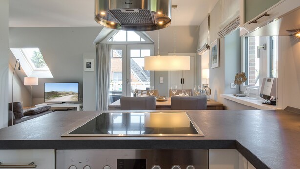 A modern kitchen with a built-in induction cooktop, a stainless steel range hood, and a digital clock displaying the time. - Ein Wohntraum & Viel Mehr, Nahe dem Meer (Sylt / OT Westerland)