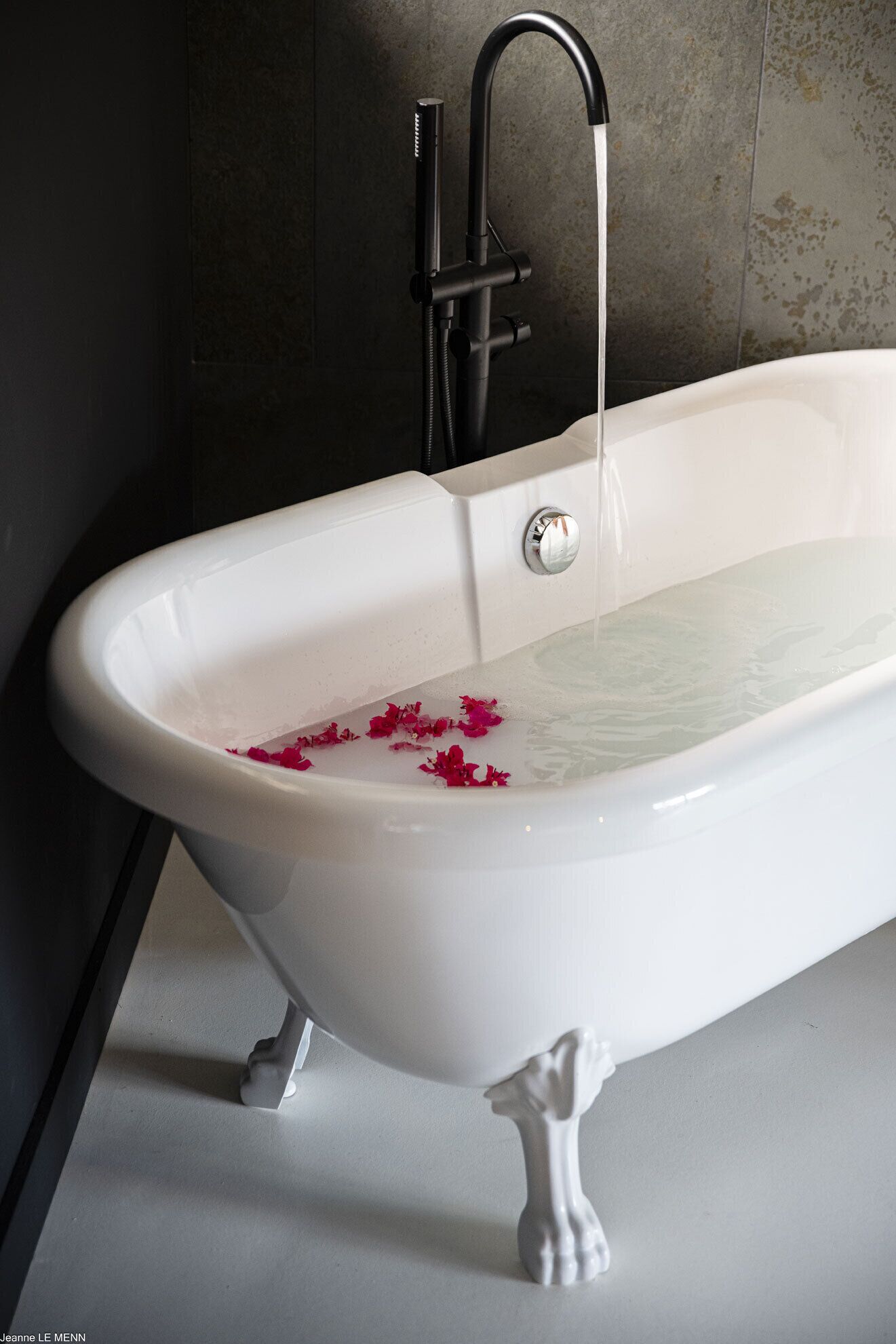 A white freestanding bathtub with a modern faucet and a single chrome knob.