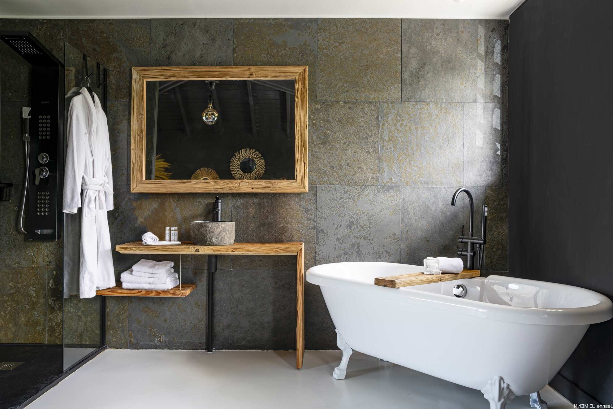 A modern bathroom with a freestanding bathtub, a wooden vanity, a large mirror, and a shower area.