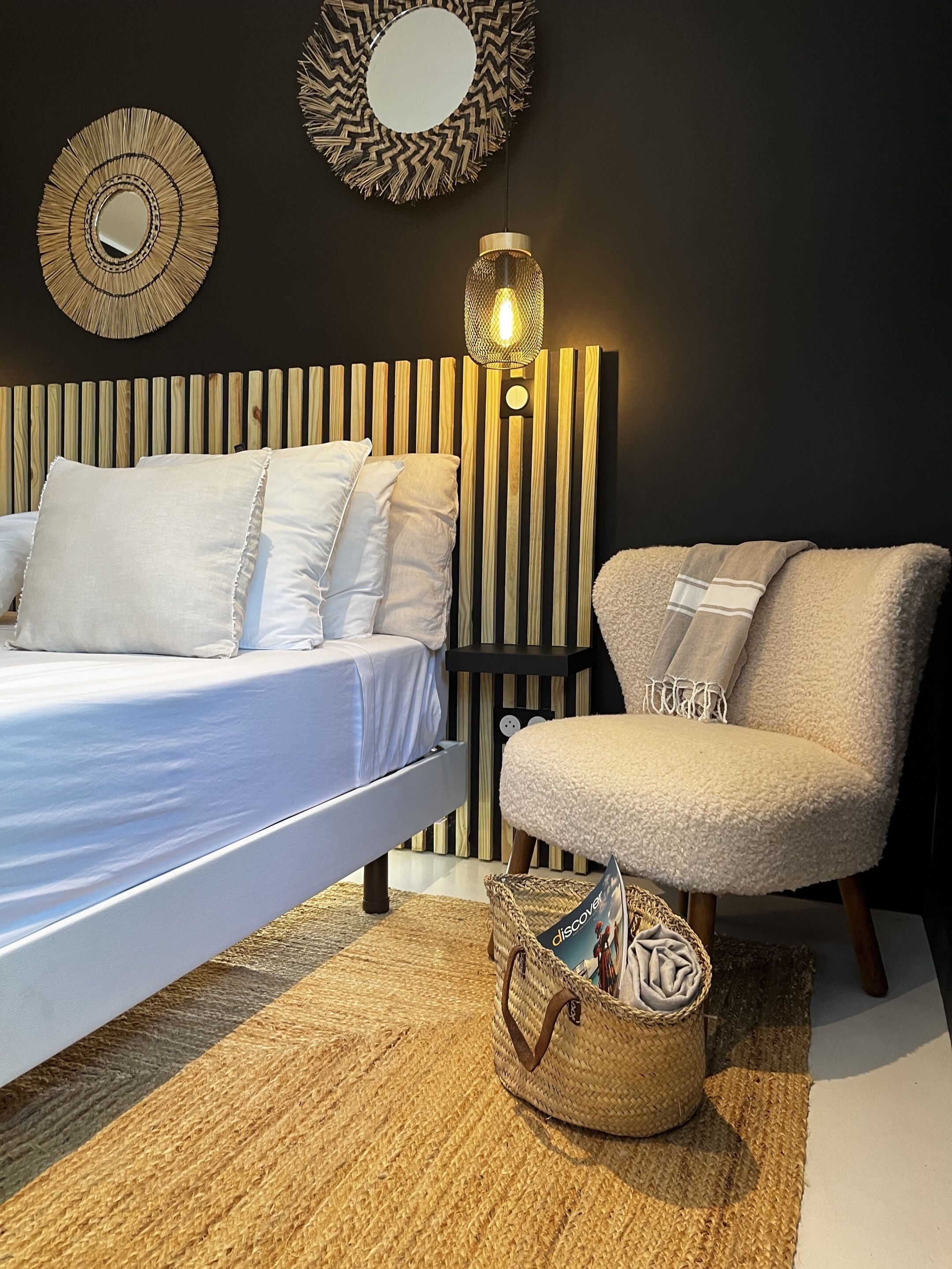 A bedroom with a bed, a chair, a lamp, and a woven basket.
