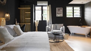 Quarto moderno com uma cama grande, uma mesa redonda, um sofá e uma banheira.