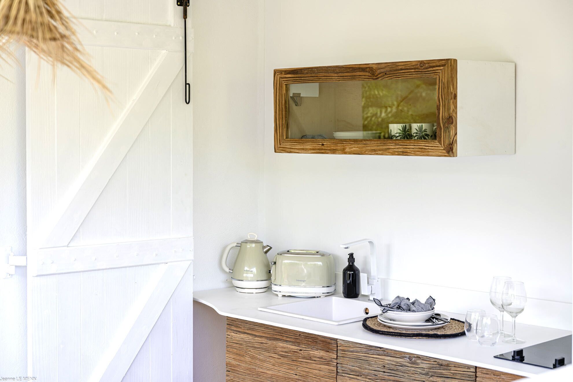 A kitchen with a white countertop, a vintage-style coffee maker, a toaster, and a wine glass.
