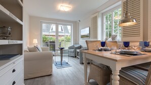 A modern kitchen with white cabinetry, a dining table set for four, and a large window with blinds. - Feinster Sylt-luxus - Nantucket-style (Wenningstedt-Braderup (Sylt))