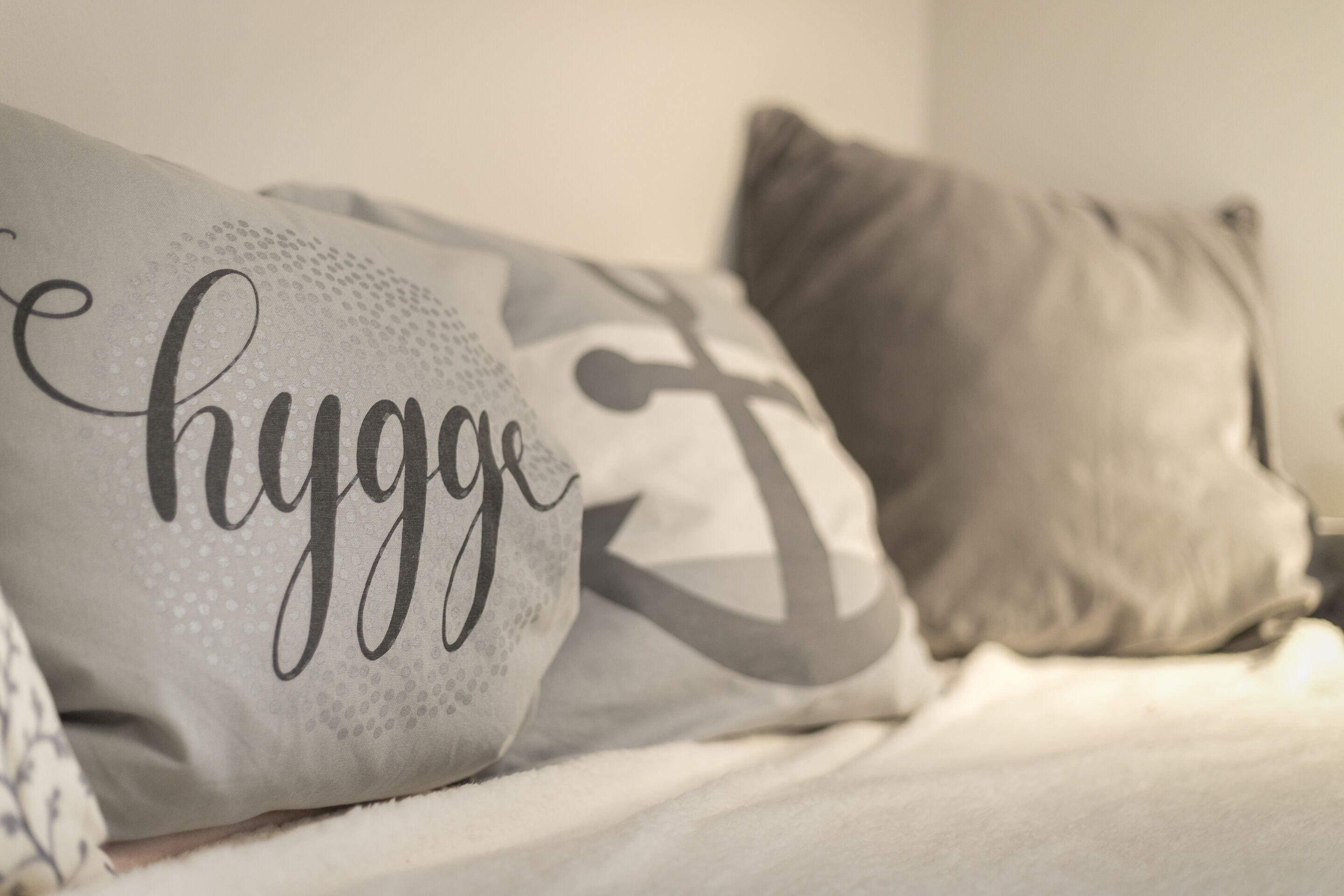 Una cama con almohadas, una de ellas con la palabra 'hygge'.