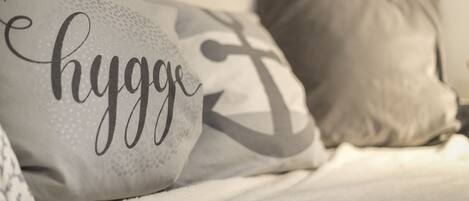 Una cama con almohadas, una de ellas con la palabra 'hygge'.