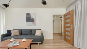 Ein Wohnzimmer mit grauem Sofa, einem Holztisch und einem Bild an der Wand.