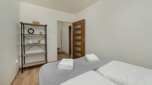 Ein Schlafzimmer mit einem Bett, einer Ablage mit Gegenständen und einer Tür zu einem anderen Raum.
