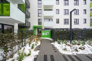 Un bâtiment moderne doté de nombreux balcons, d’une entrée sécurisée et d’un chemin menant à l’entrée.