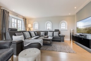 Een moderne woonkamer met een hoekbank, een salontafel en een flatscreen televisie.
