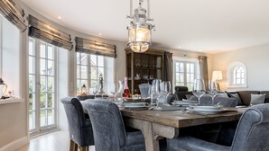 Comedor con mesa de madera dispuesta para seis personas, rodeado de sillas tapizadas en gris.