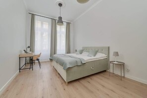 A bedroom with a bed, a desk, and a chair.