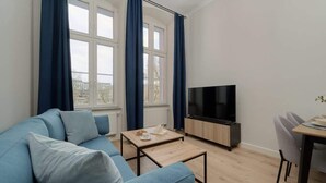Un salon comprenant un canapé, une table basse, un téléviseur et un coin repas avec des chaises.