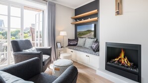 A modern living room with a fireplace, seating area, and a view of the outdoors.
