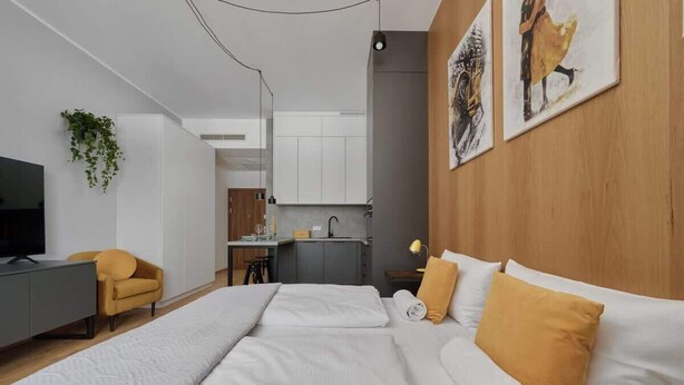 Ein modernes Hotelzimmer mit einem Bett, einem Schreibtisch, einem Stuhl und einer kleinen Küchenzeile.