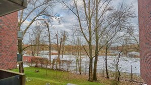 Blick aus einem Fenster auf eine Wiese mit Bäumen und einem Backsteinhaus.
