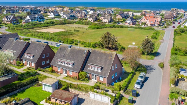 Een woonwijk met huizen, een weg en uitzicht op zee.