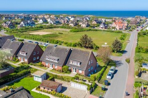 A residential area with houses, a road, and a view of the sea.