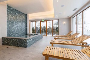A spa area with a mosaic wall, a hot tub, and wooden loungers.
