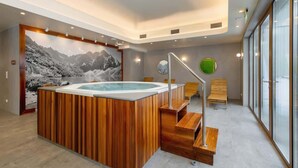 Un moderno espacio de spa con una bañera de hidromasaje de madera, una escalera y un ventanal grande con vistas al exterior.