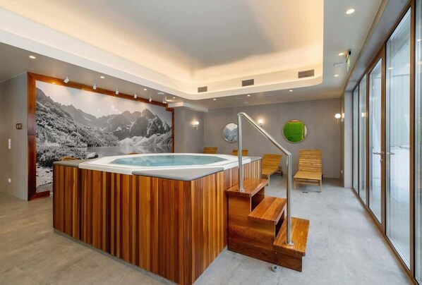 A modern spa area with a wooden hot tub, a staircase, and a large window providing a view of the outdoors.