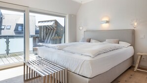 Ein modernes Schlafzimmer mit einem großen Bett, einer Bank und Blick ins Freie.