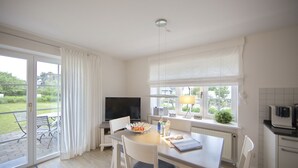 A modern kitchen with a dining area, large windows, and a view of the outdoors.