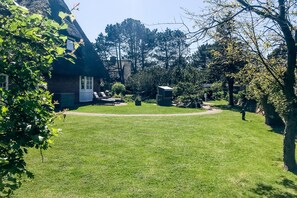A well-maintained lawn with a thatched-roof house, a picnic table, and a small shed. - Das Somerhüs Wird Ihnen Nicht nur bei Warmen Temperaturen Urlaubsfreude Bereiten (Wenningstedt-Braderup (Sylt))