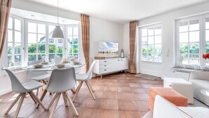 A bright dining area with a round table, white chairs, and a white cabinet.