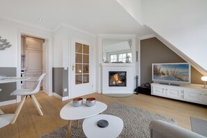Cozy living space with a fireplace, comfortable seating area, and a large mirror above the hearth.
