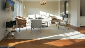 Ein Wohnzimmer mit einer Couch, Sesseln, einem Teppich, einer Chandelüster und einem Kamin.