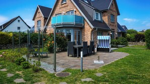 Ein zweistöckiges Haus mit Ziegelaußenwand, einem Balkon und einer Terrasse mit Gartenmöbeln.