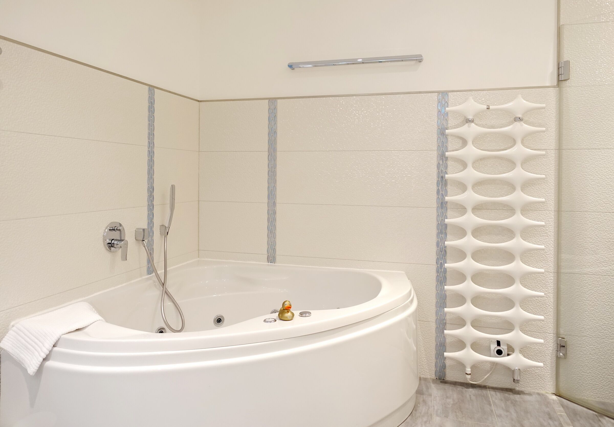 Ein modernes Badezimmer mit einer freistehenden Badewanne, einem Handtuchhalter und einer dekorativen Wandverkleidung.