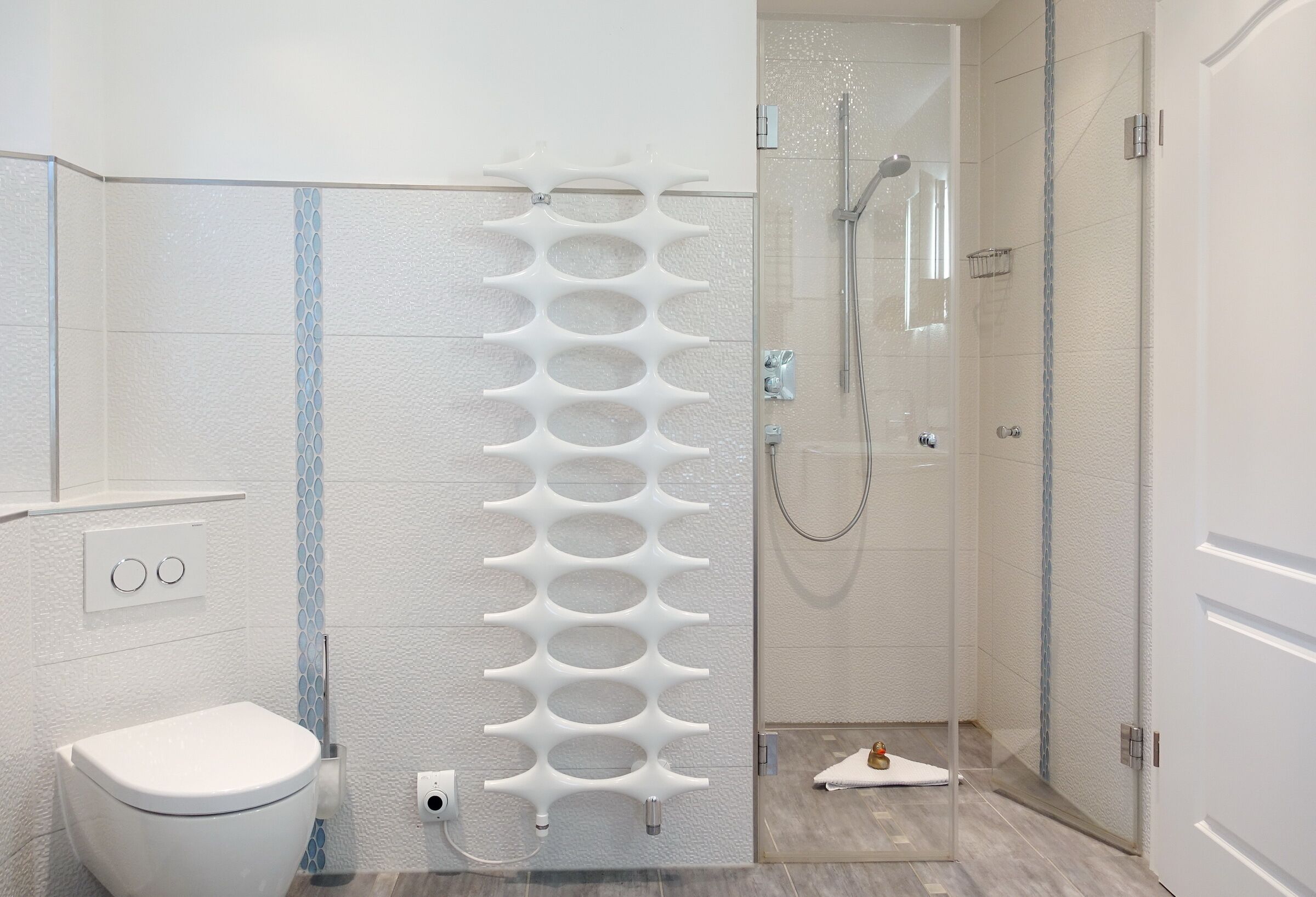 Un baño moderno con inodoro blanco, cabina de ducha con mampara de vidrio y lavabo blanco.