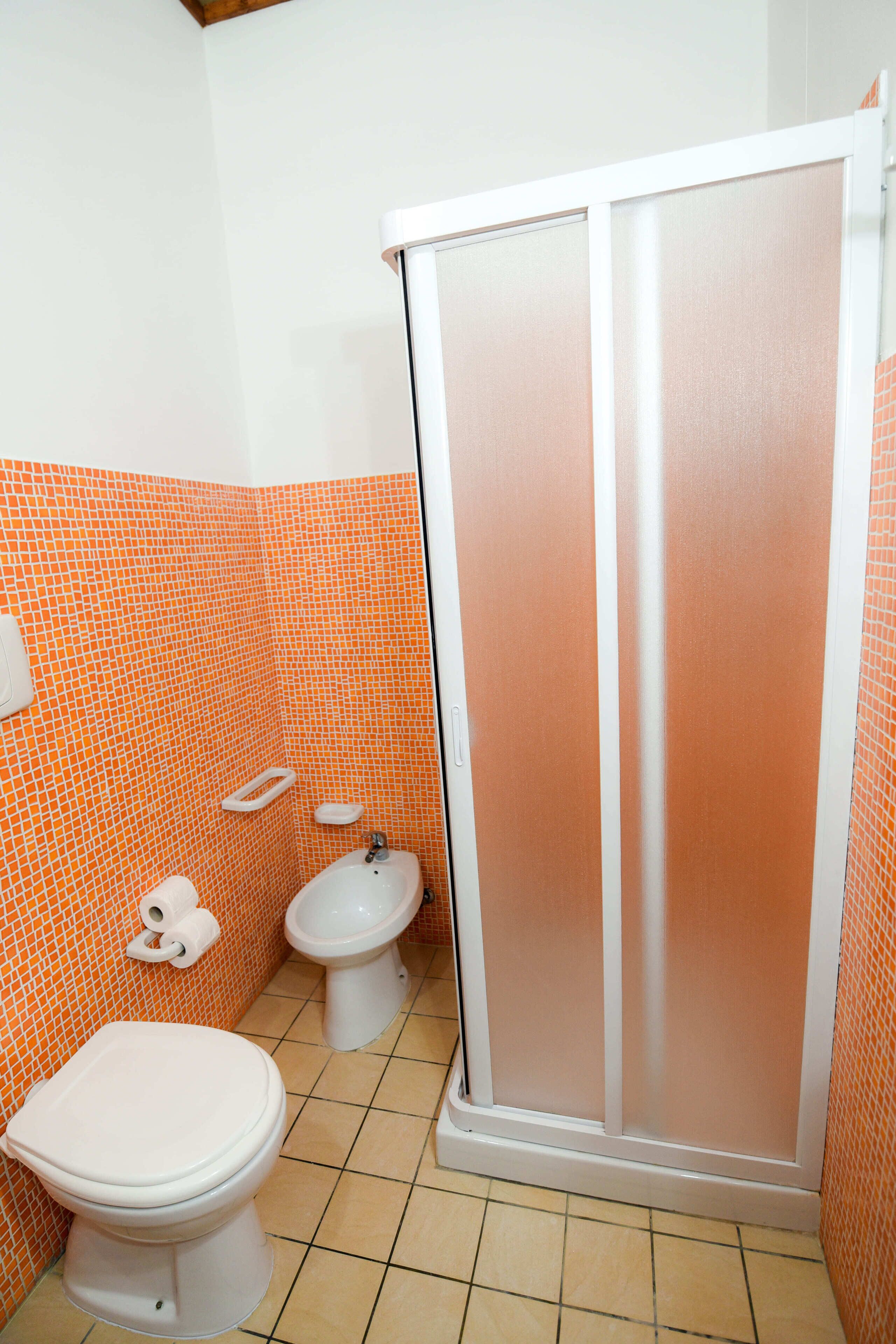 A bathroom with a toilet, bidet, and shower enclosure.