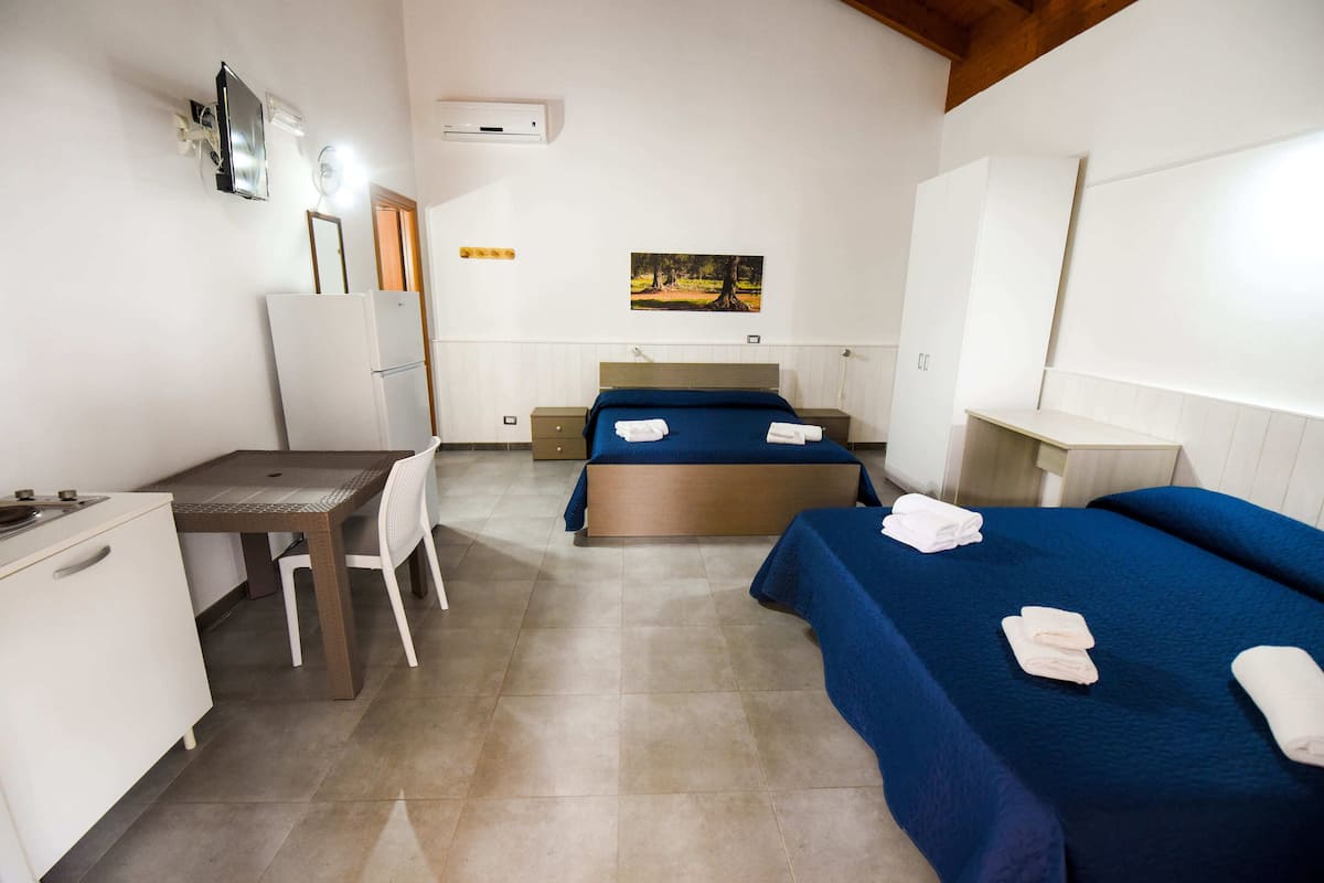 Een hotelkamer met een bed, een bureau, een stoel, een koelkast en een tv aan de muur.