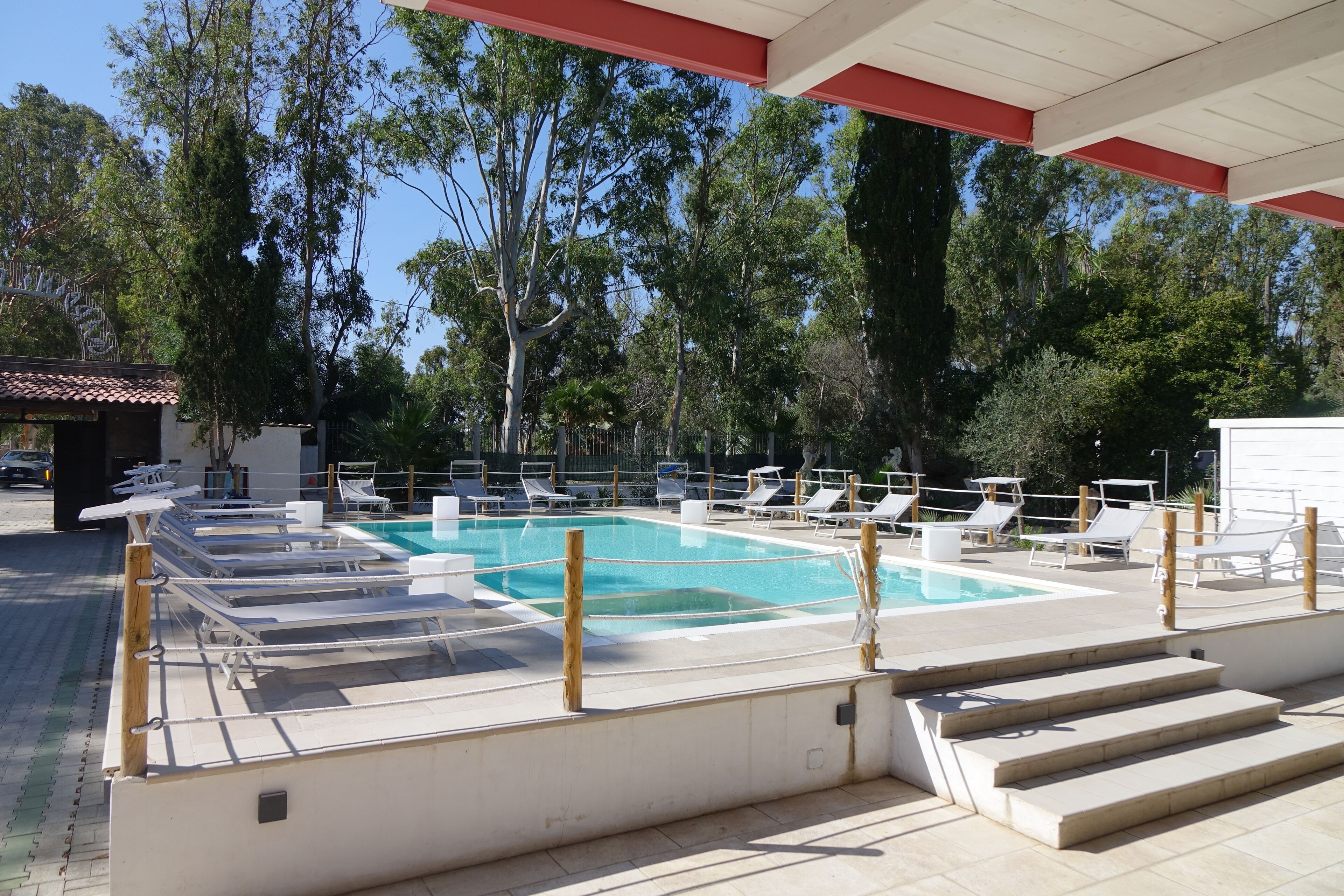 En swimmingpool med liggestole og et overdækket område.