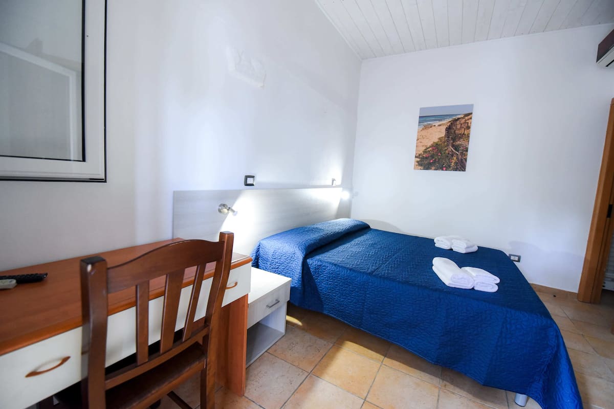 Een slaapkamer met een bed, een bureau en een stoel.