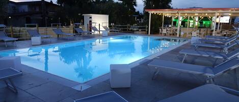 Een seizoensgebonden buitenzwembad en ligstoelen